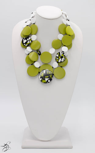 THREE LAYERS OF A BEAUTIFUL AND UNIQUE GREEN, BLACK AND WHITE SPOTTED CIRCLED PEBBLES WITH A WHITE BUTTON AND WHITE CHORD CLOSURE.  ONE OF A KIND NECKLACE THAT LAYS LIGHT ON THE NECK.