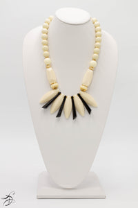 BLACK AND IVORY LAPELS ADORNED WITH IVORY SPHERES AND CYLINDER SHAPED IVORY BEADS